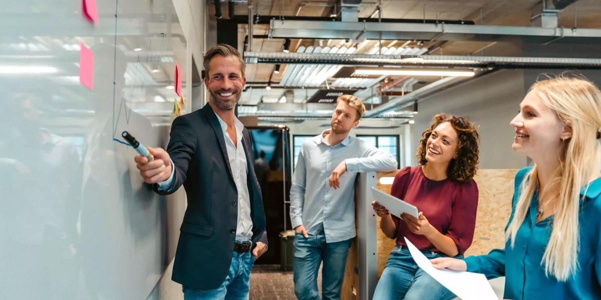 Smiling employees pointing at whiteboard in meeting with colleagues at office